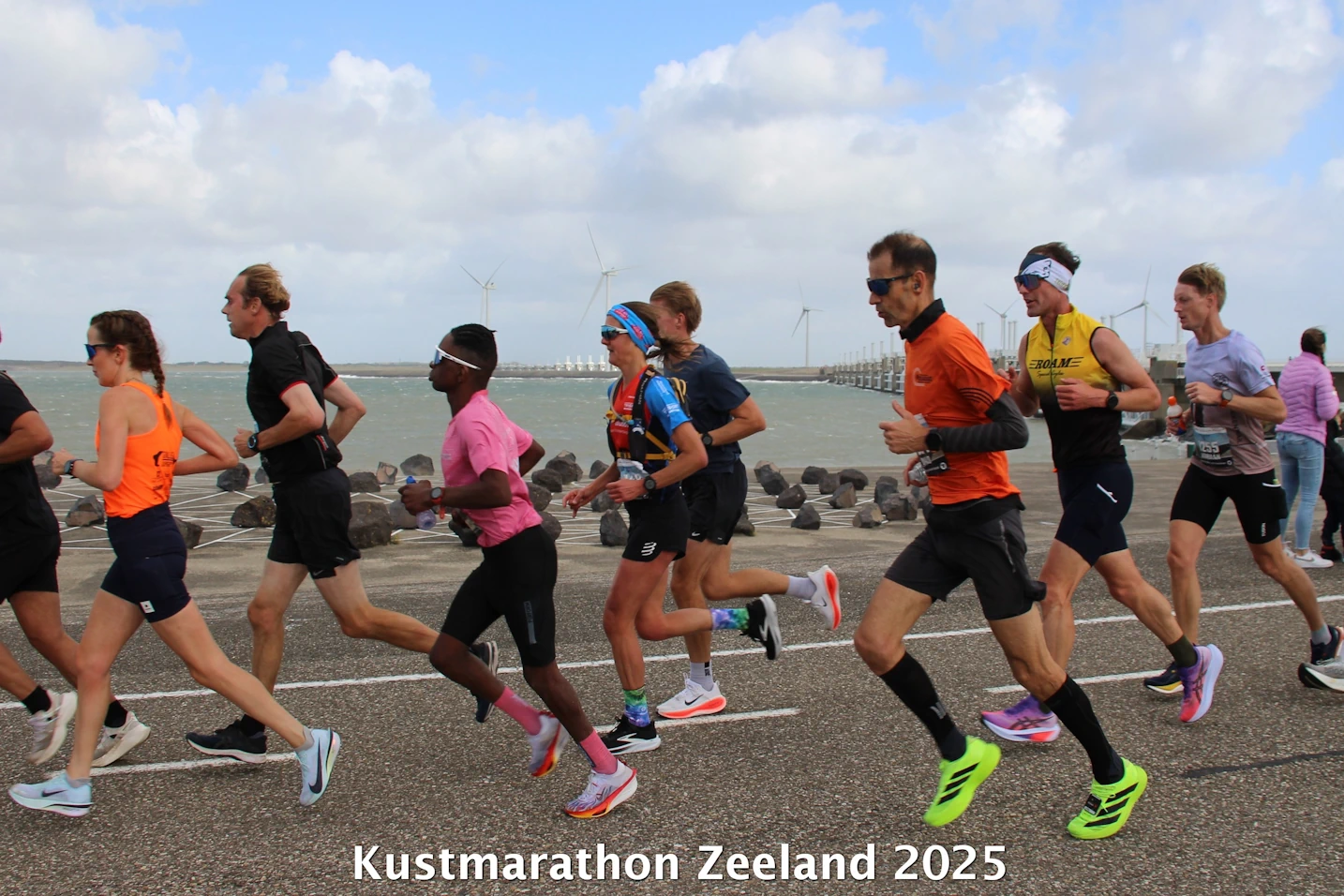 Lopers vechten tegen windkracht 7 op het strand tijdens de Kustmarathon Zeeland