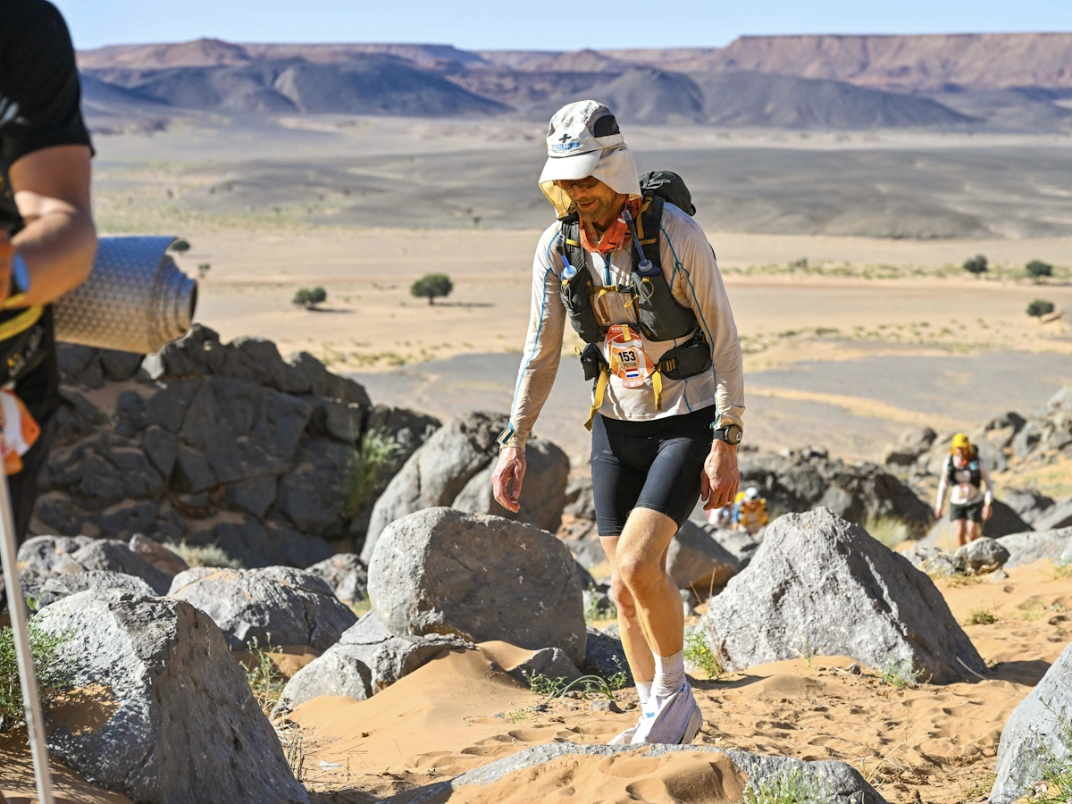Loper alleen tussen zand en rotsen tijdens de Marathon des Sables