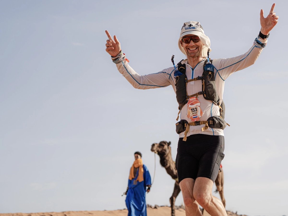 Peter met een kameel in de Sahara tijdens de Marathon des Sables