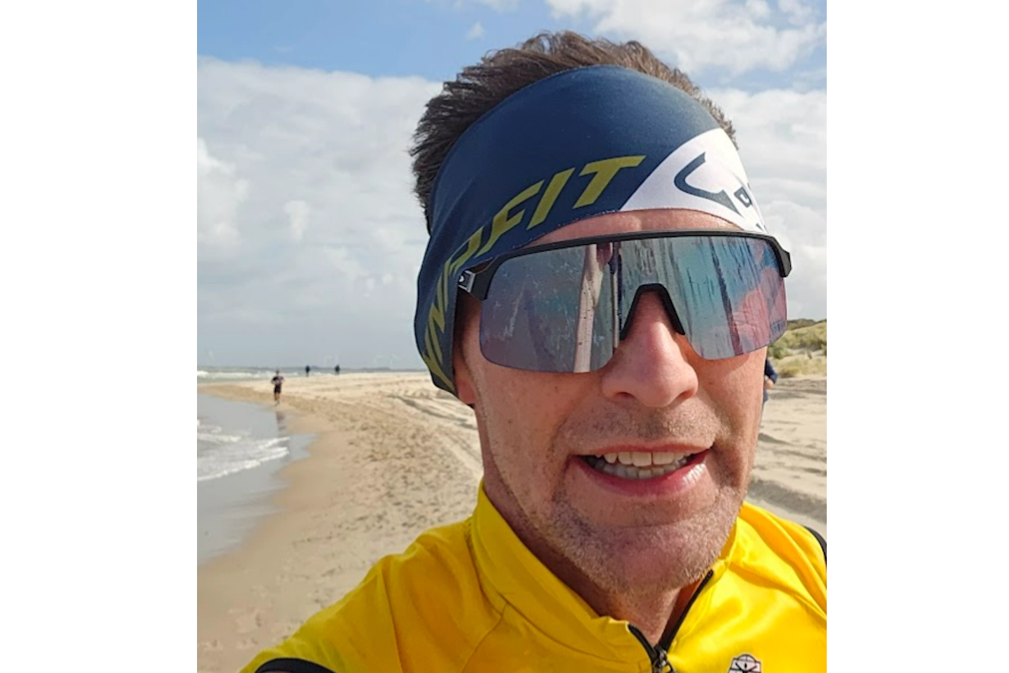 Peter op het strand bij de finishvlaggen na hardlopen met storm tijdens de Kustmarathon Zeeland