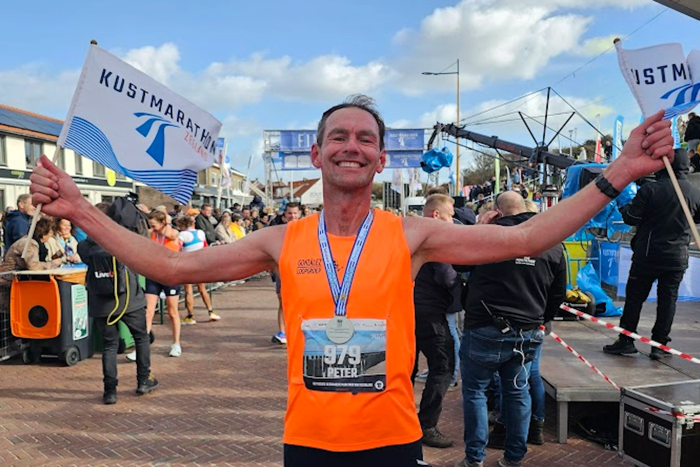 Euforisch moment van Peter bij de finishvlaggen na hardlopen met storm en tegenwind